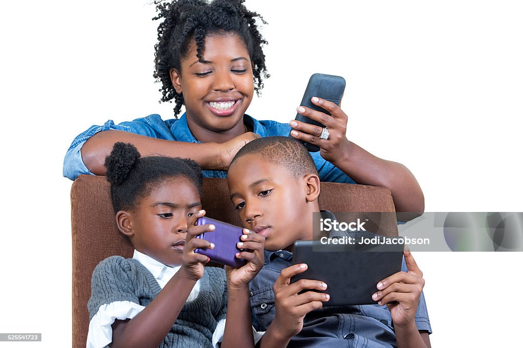 African American mother with her children using cell phones An African American mother leans over her children sitting on a chair using cell phones and tablets.  Shot with Canon 5D Mark 3  rr African Ethnicity Stock Photo