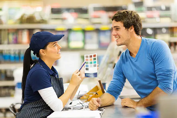 Photo of paint store assistant helping customer choose paint color