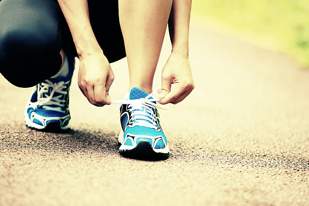 istock woman runner tying shoelaces on trail 525546085