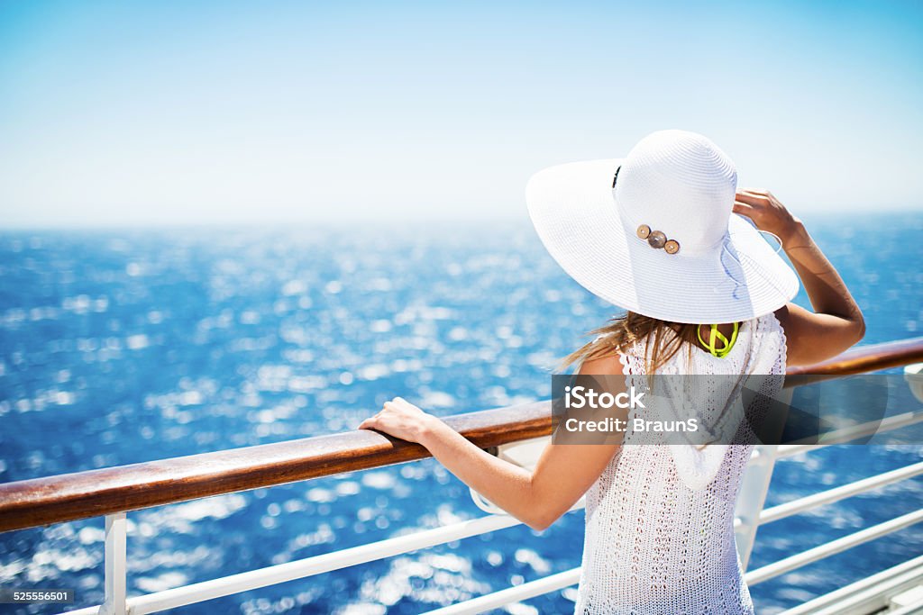 On a cruise. Unrecognizable woman with hat on a cruise ship looking at the view. Cruise - Vacation Stock Photo