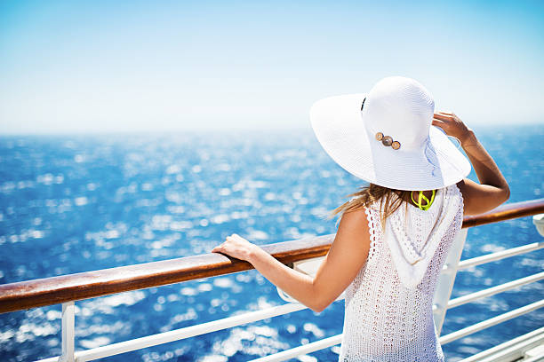 On a cruise. Unrecognizable woman with hat on a cruise ship looking at the view. cruising stock pictures, royalty-free photos & images