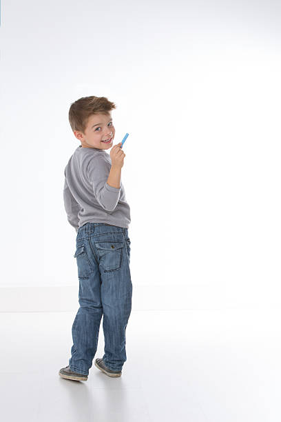 sly child smiling to the camera little kid intends to write something on empty wall ass boy stock pictures, royalty-free photos & images
