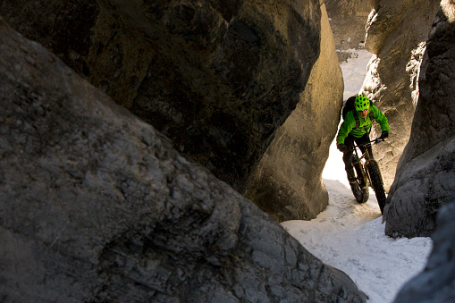 A male mountain biker enjoys a winter fat bike ride through a canyon in Alberta, Canada.