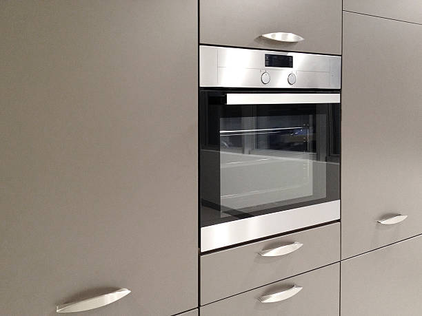 Modern metallic stainless steel oven at the kitchen with kitchen cabinets