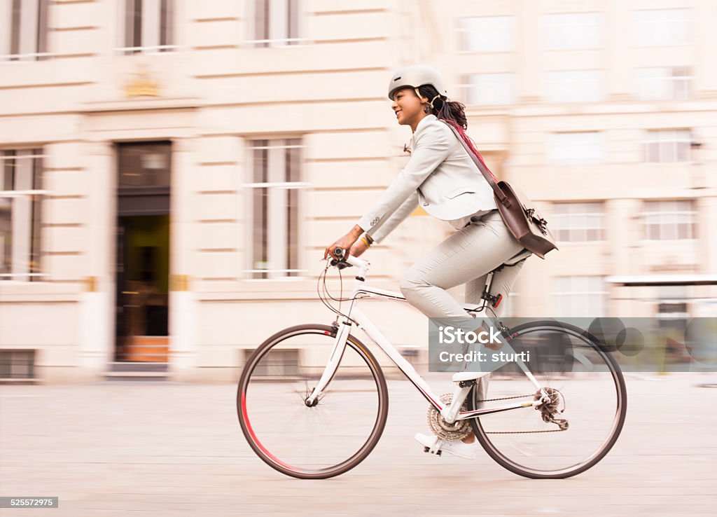 cycling businesswoman commuter a young businesswoman or office worker is cycling through the business district in a trouser suit and a helmet. Cycling Stock Photo