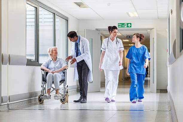 medico infermiere ospedale paziente senior femmina in un corridoio di - servizio sanitario nazionale britannico foto e immagini stock