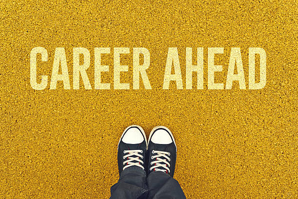 istock Young man standing at Career Ahead sign 525573153