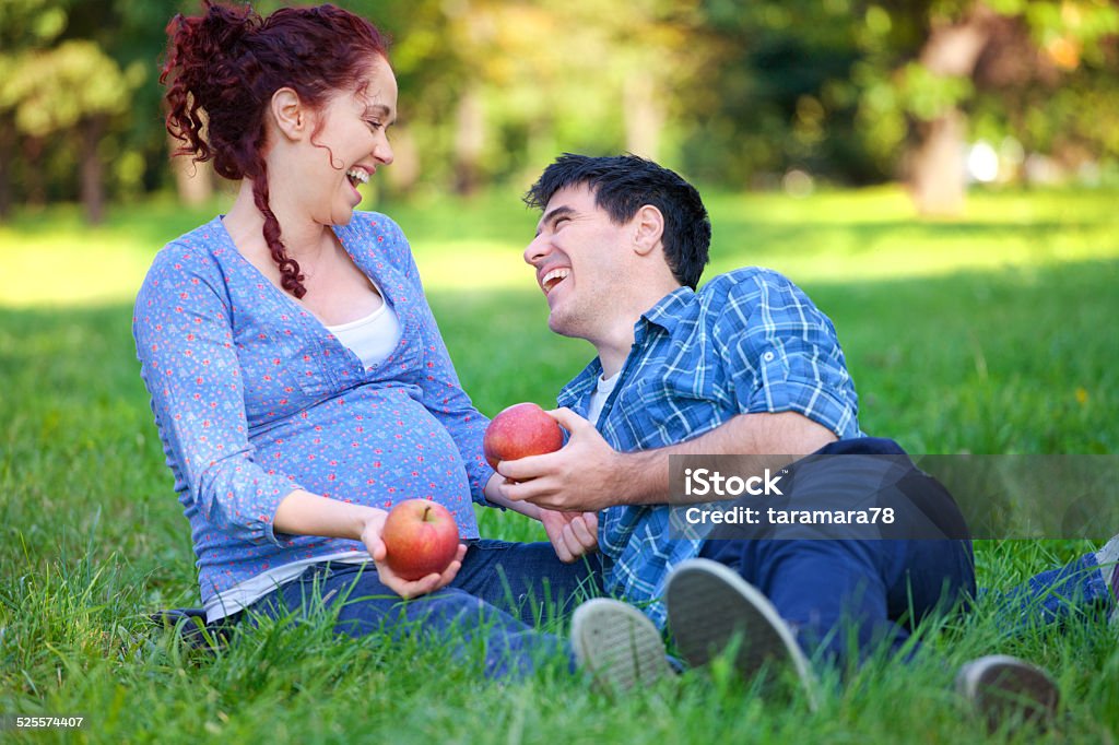 Couple with apples Cheerful young pregnant couple eat apple in park 30-39 Years Stock Photo