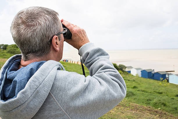 istock Man looking out to sea with binoculars 525574417