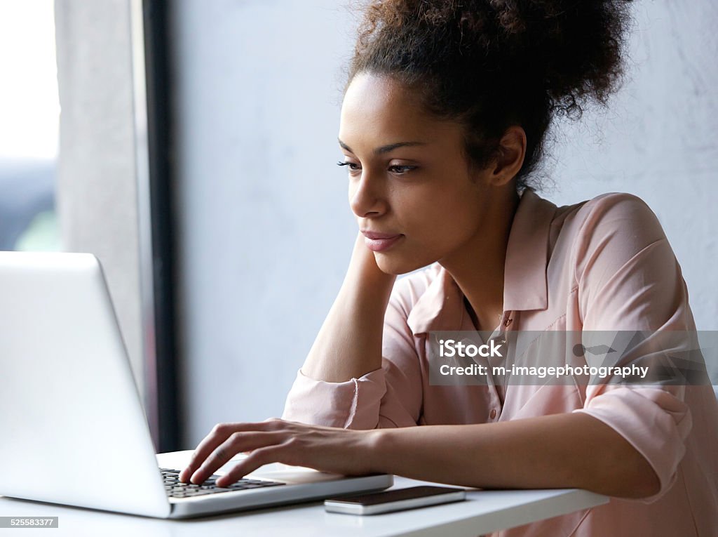 Young black woman looking at laptop Close up portrait of a young black woman looking at laptop Women Stock Photo