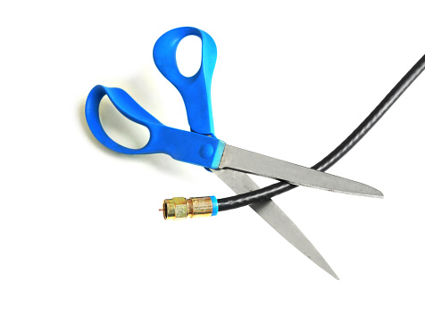Scissors cutting through a coaxial cable - cut the cable tv concept