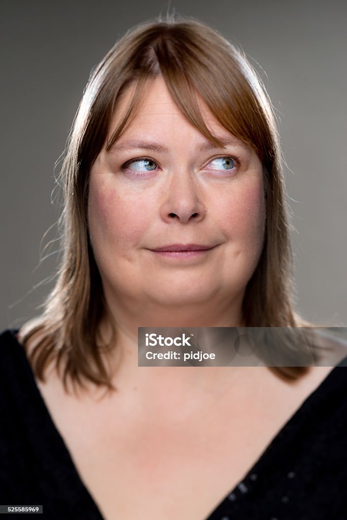 Happy real woman Shot with a shift tilt lens, focus on the eyes, looking to the left, against a gray background. 40-49 Years Stock Photo