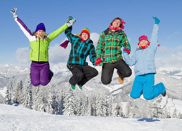 quatre jeunes gens en vêtements d'hiver de sauter sur les pistes de ski - people group of people friendship salzburg photos et images de collection