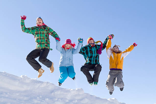 quatro jovens em roupas de inverno pulando na neve - people group of people friendship salzburg - fotografias e filmes do acervo