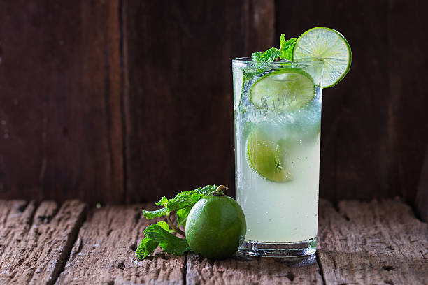 Mojito cocktail Mojito cocktail in a restaurant on a rustic wooden table highball glass stock pictures, royalty-free photos & images