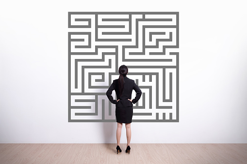 Back view of business woman look maze with white wall background, asian