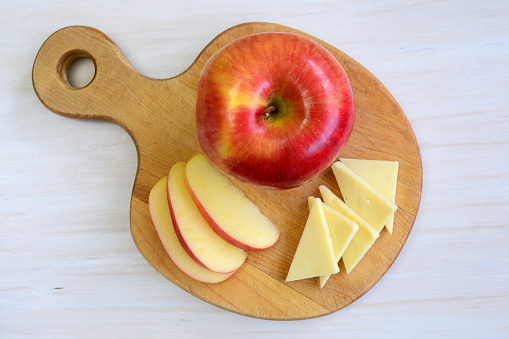 Beautiful honeycrisp apple on unique apple shaped cutting board on rustic white background