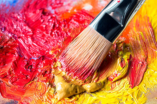 istock Paintbrush with yellow oil paint on a classical palette 525627895