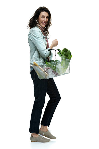 istock Cheerful woman holding vegetable basket & walking 525630783