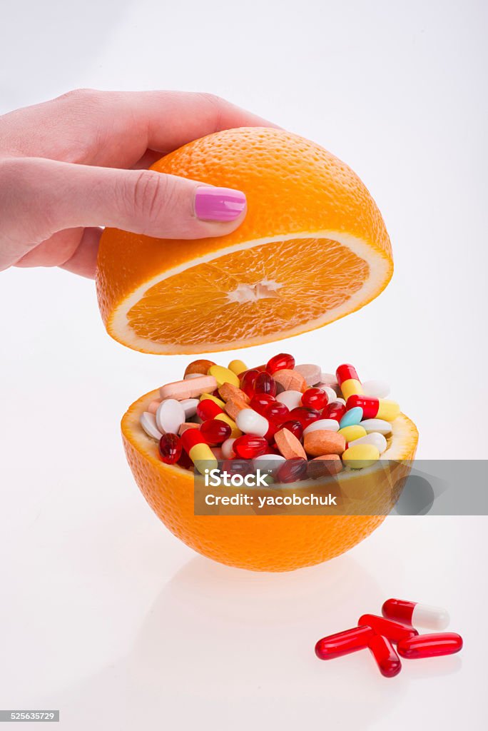 Health and pills Half of an orange filled with the different pills lying on the white surface another is over it. Isolated on the white background Antioxidant Stock Photo