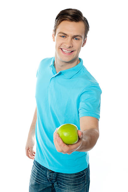 istock Good looking healthy guy offering a green apple 525640055