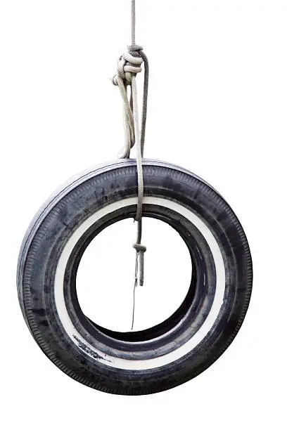 Isolated tire swing hanging on rope. Vertical.