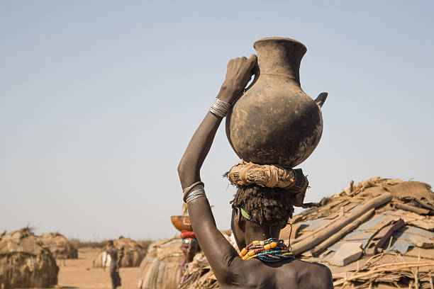 Omo Valley, Ethiopia - December 28, 2008: Young woman carries a container with water on his head in his village near Turmi in the Omo Valley, Ethiopia.
