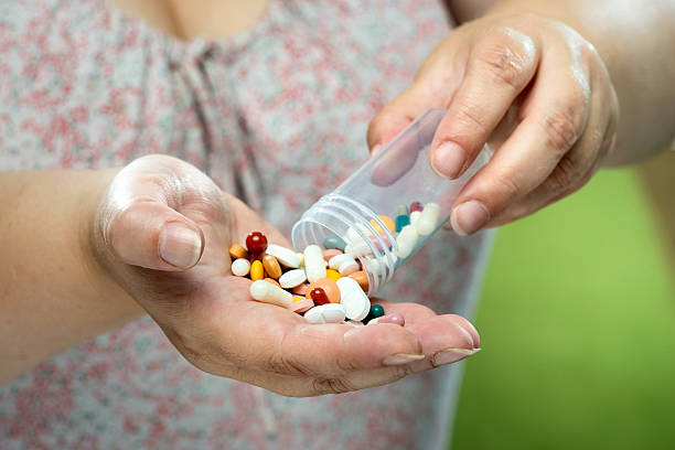 istock Older women pouring medicine into hand. 525651817