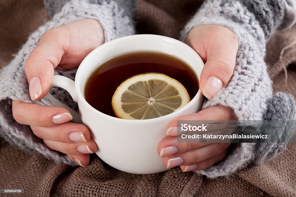 Tea with lemon on a cold day Woman's hand holding cup of tea with lemon on a cold day Tea - Hot Drink Stock Photo