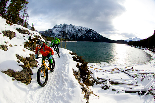 A woman and man enjoy a winter fat bike ride in Banff National Park, Alberta, Canada.