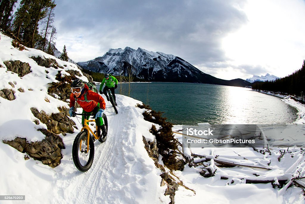 Snow Biking Couple A woman and man enjoy a winter fat bike ride in Banff National Park, Alberta, Canada. Winter Stock Photo