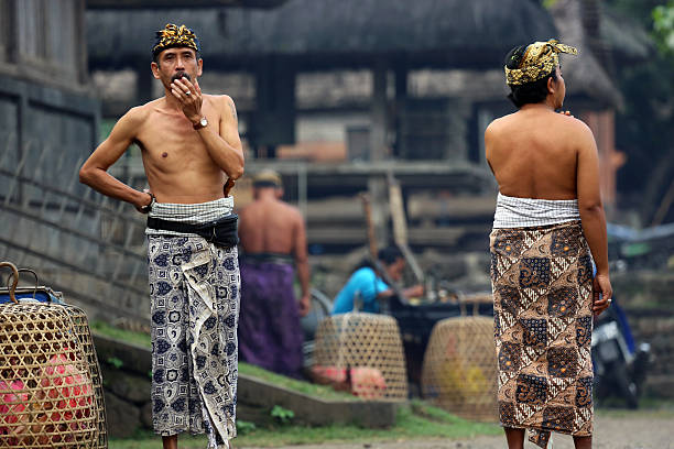 Tenganan, Indonesia - August 23, 2014: A pair of men wait for a traditional ceremony at the Tenganan Village, once one of the most secluded societies in Indonesia, it is now a tourist attraction due to its culture, architecture, and crafts. A visit is a step back in time.