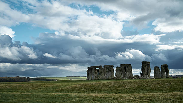 Stonehenge Beneath Stormy Skies A dramatic sky looms over the ancient neolithic monument of Stonehenge in Wiltshire, England.  stone age stock pictures, royalty-free photos & images