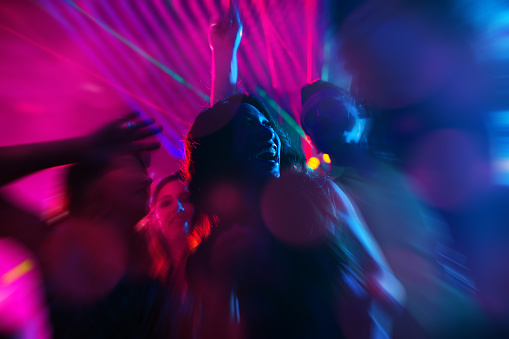Group of party people - a man and women - dancing in a disco club to the music