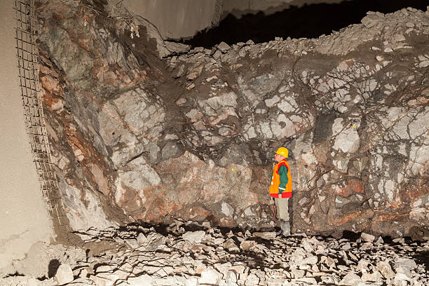 Geologist evaluating rock face Tunneling/geotechnical engineer wearing safety gear inspecting rock face during tunneling works. bedrock foundation stock pictures, royalty-free photos & images