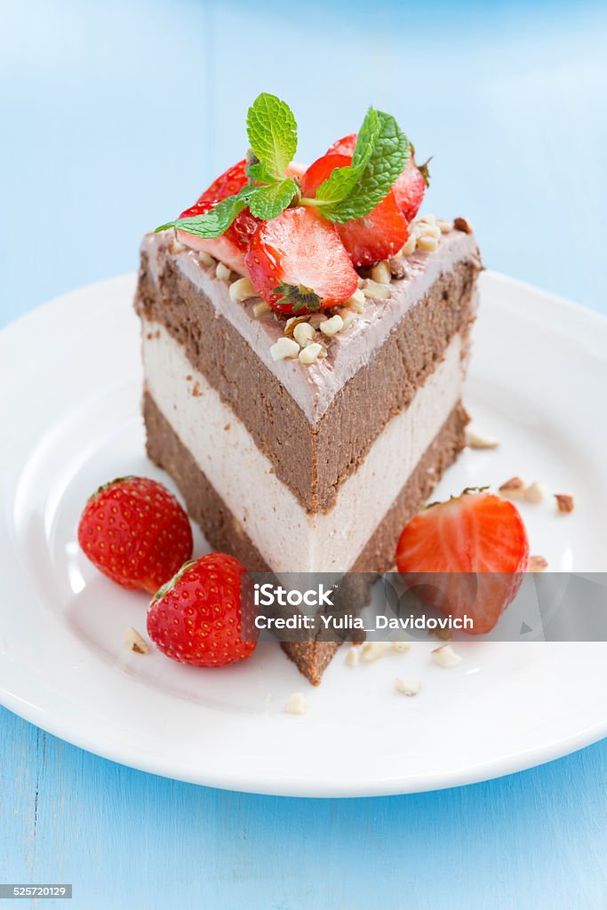 piece of chocolate cake with fresh strawberries piece of chocolate cake of three layers with fresh strawberries on white plate, selective focus, vertical Bakery Stock Photo