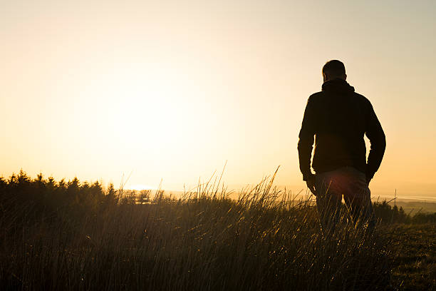 istock Man stood in countryside with late afternoon sun flare 525728492