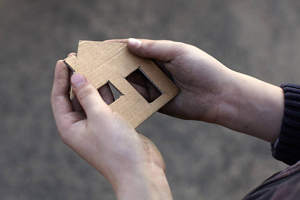 homeless boy holding a cardboard house