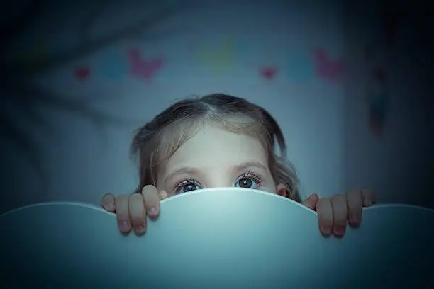 Photo of scared little girl in her bed