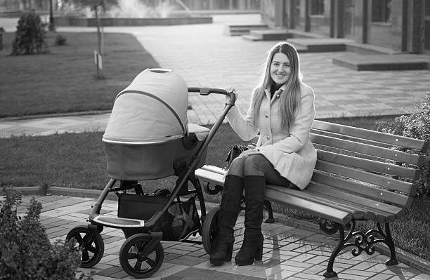 istock young mother sitting on bench with baby stroller 525737944