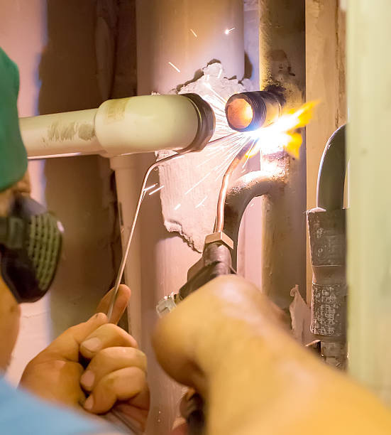 The plumber makes gas welding of a pipe stock photo