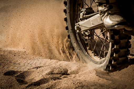 Dirt bike speeding on a gravel and sand track splashing sand