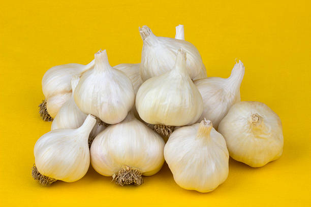 Garlic Garlic on yellow tablecloth. acrid taste stock pictures, royalty-free photos & images