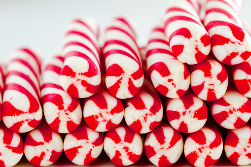 Close up of rows of ends of red and white striped candy canes and peppermint sticks