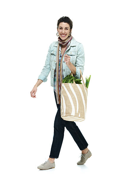 istock Cheerful woman holding vegetable bag & walking 525756249