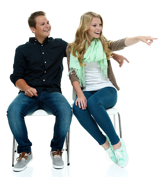 istock Cheerful couple on chair & pointing away 525756355