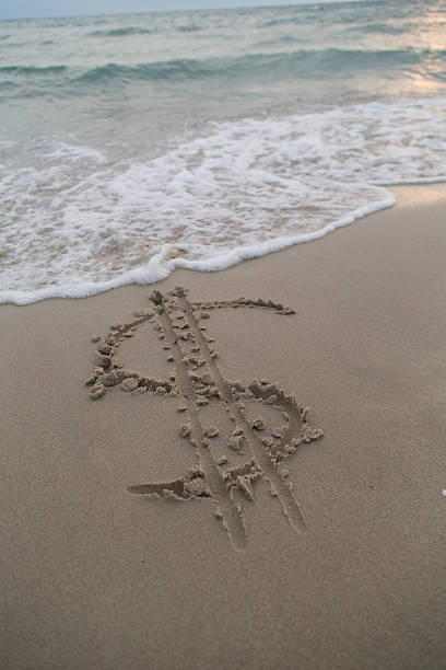 istock Dollar sign in the sand being washed away 525771173