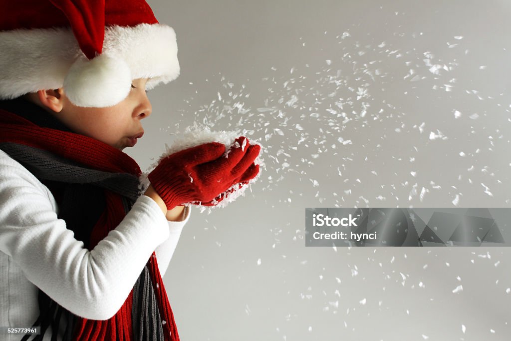 Boy in santa claus hat blowing snowflakes Littel boy in santa claus hat and scarf and gloves blowing snowflakes Christmas Stock Photo