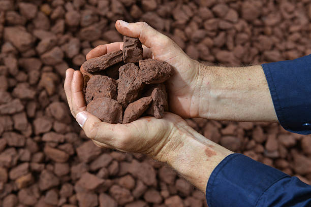 Two hands holding an iron ore sample. A person holding a handful of crushed iron ore close to the camera.  Reclaimer stock pictures, royalty-free photos & images