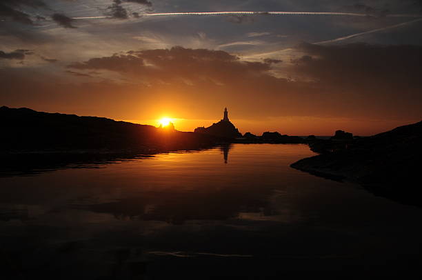 La Corbiere lighthouse, Jersey, U.K. Wide angle image of coastal structure and sunset reflected in a pock pool. lighthouse lighting equipment reflection rock stock pictures, royalty-free photos & images